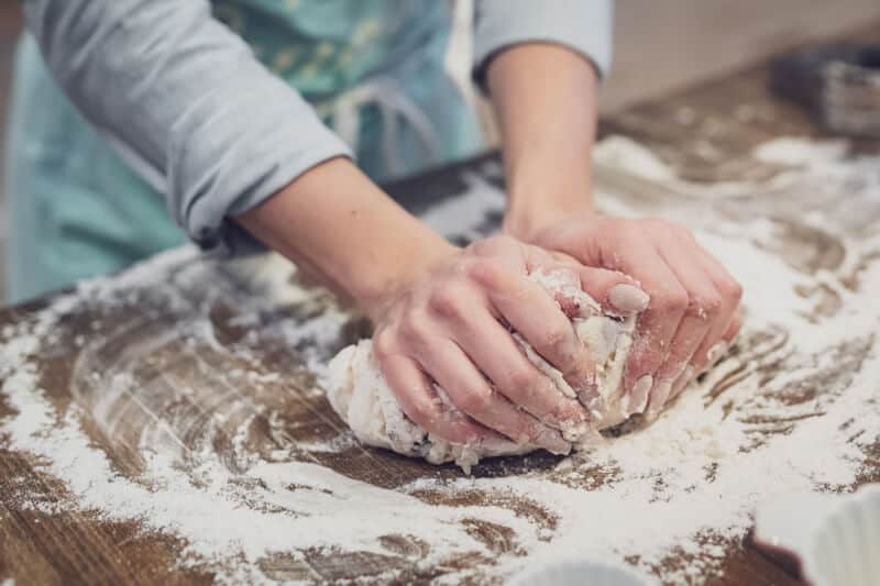 Hands kneading dough on a floured surface
