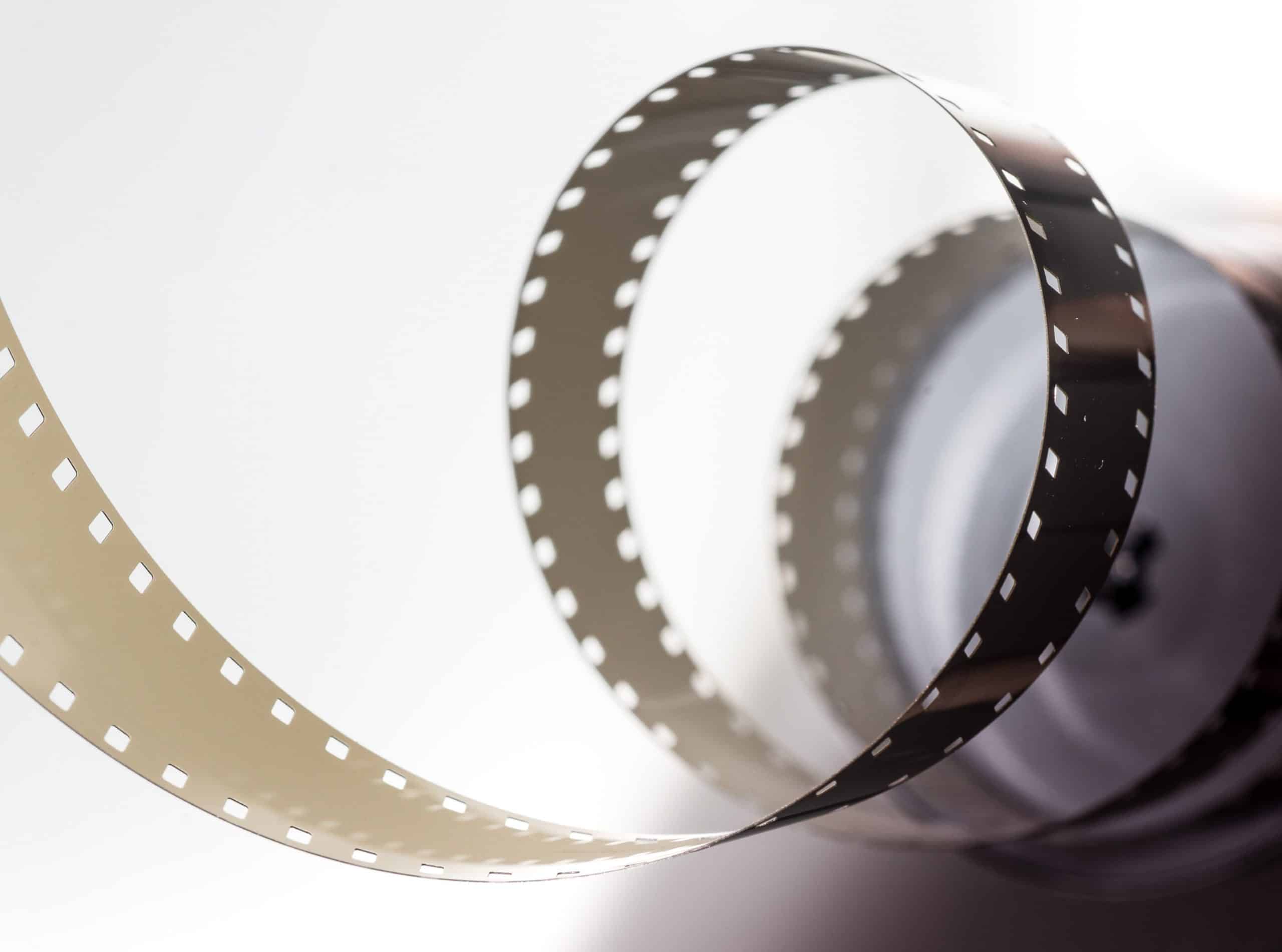 A reel of cinema film unwound in loose coils against a plain white background