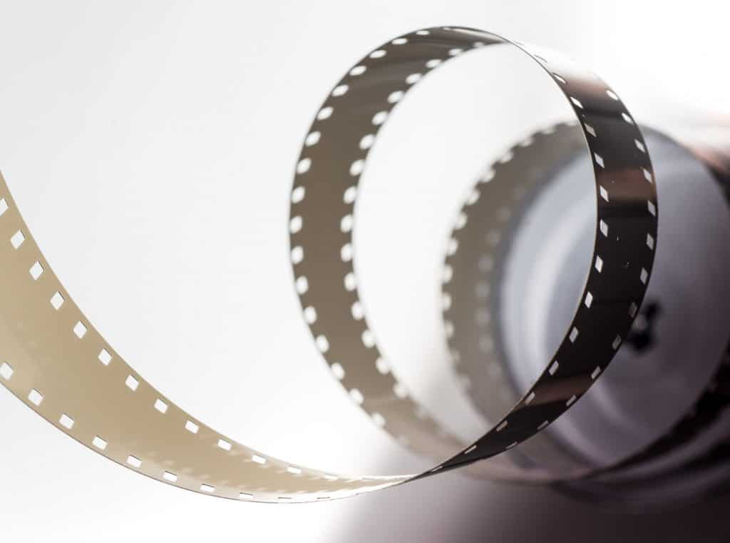 A reel of camera film unwound in loose coils against a plain white background
